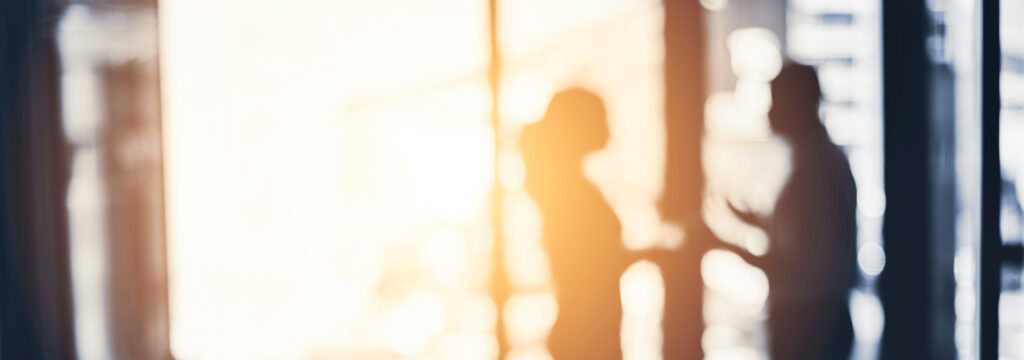 Defocused people set against a sunset in a modern office environment conversing about cyber security in the modern age