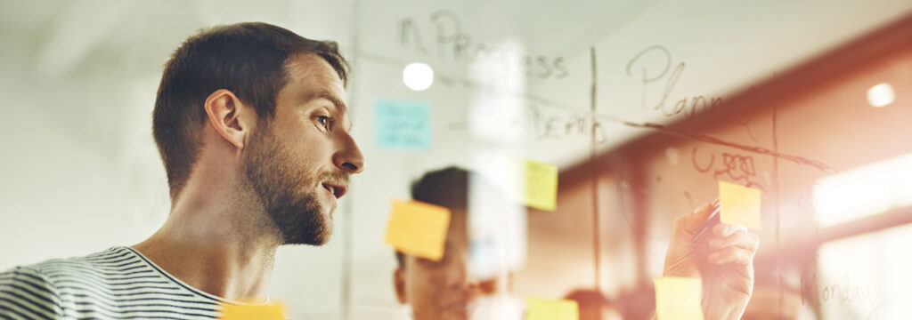 Young charity worker using a whiteboard and marker to illustrate how managed IT services are helping not-for-profit organisations benefit from tech adoption