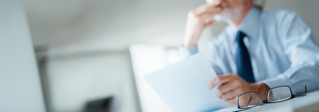 Businessman seated at a desk contemplating how to conduct IT audits, and why they are important