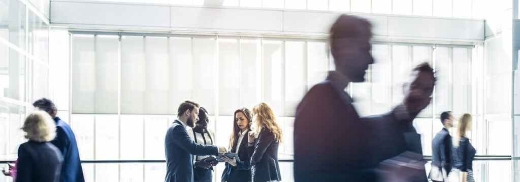 A group of young executives standing in the concourse of a modern office space discussing transforming modern business with Azure SQL services