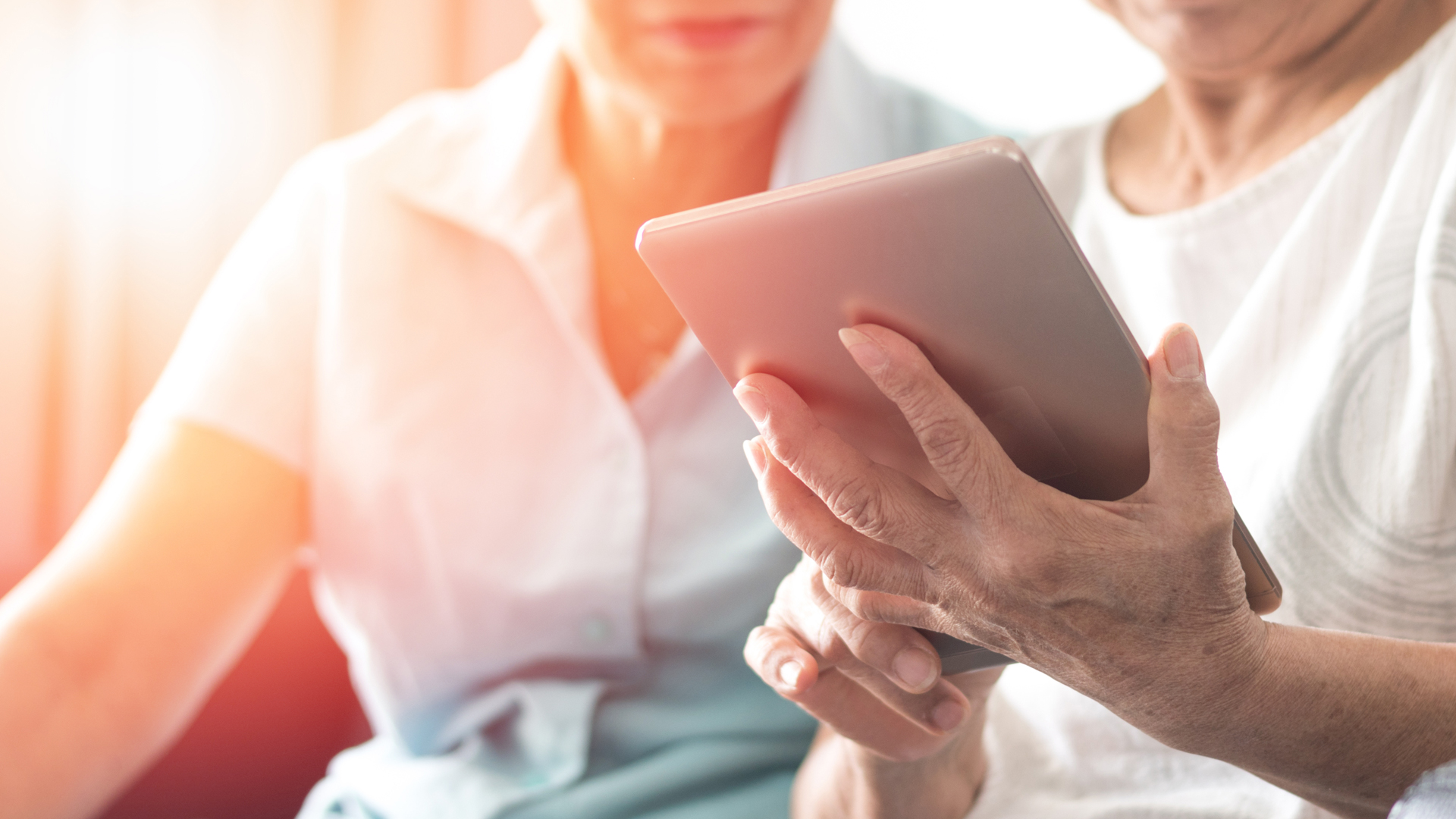 Close up image of two elderly people viewing a tablet device