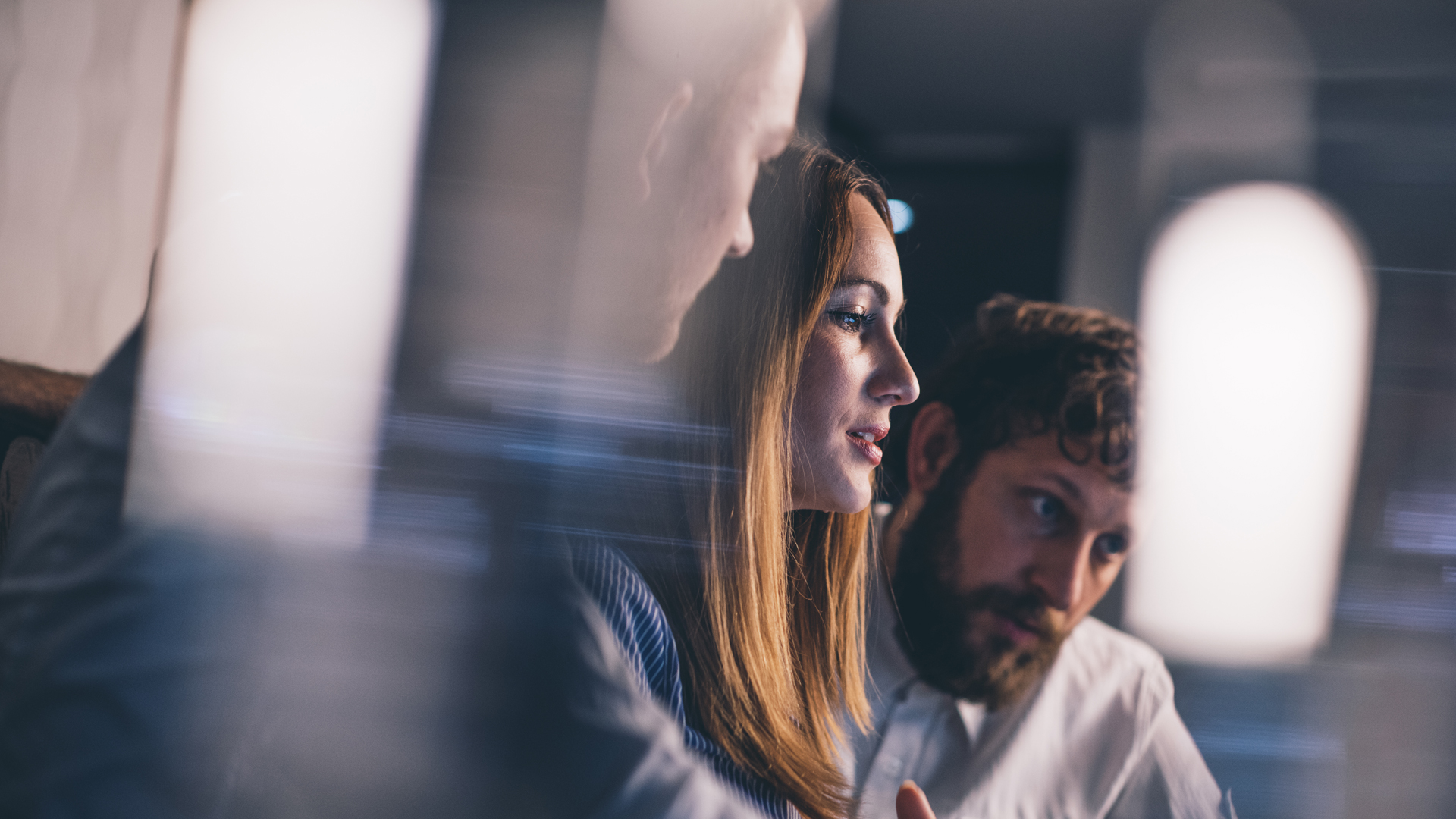 A group of young professionals seated around a desktop display whilst discovering Microsoft Viva Goals