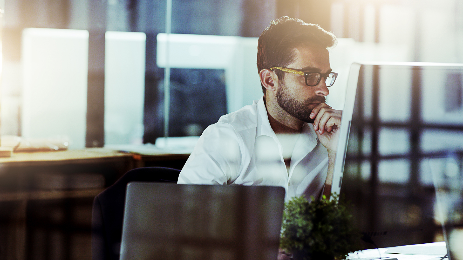 A professional services expert viewing a desktop monitor in a modern office space while considering the real benefits of SharePoint for file storage