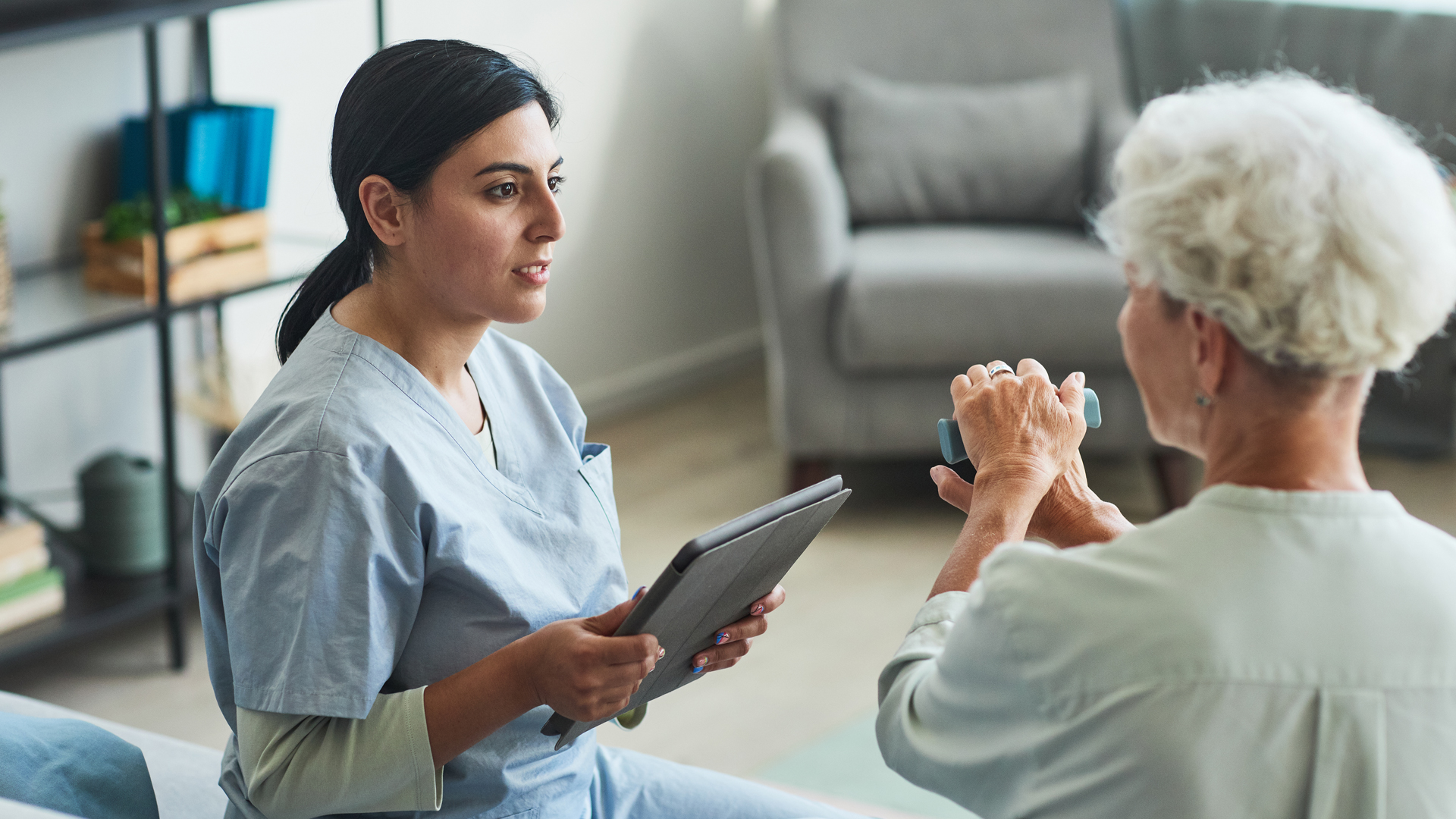 Young medical professional holding a digital tablet device while speaking with an elderly woman about why compliance shouldnt be an afterthought